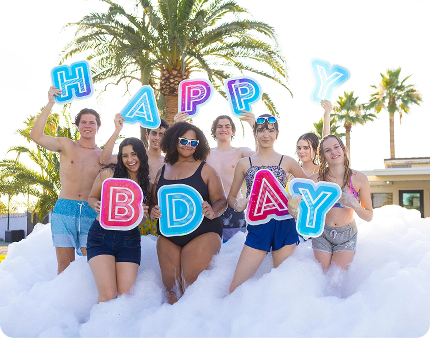 Group celebrating birthday with foam and signs